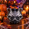 Glossy black sculpted cauldron treat bowl filled with wrapped Halloween candy on a candlelit table